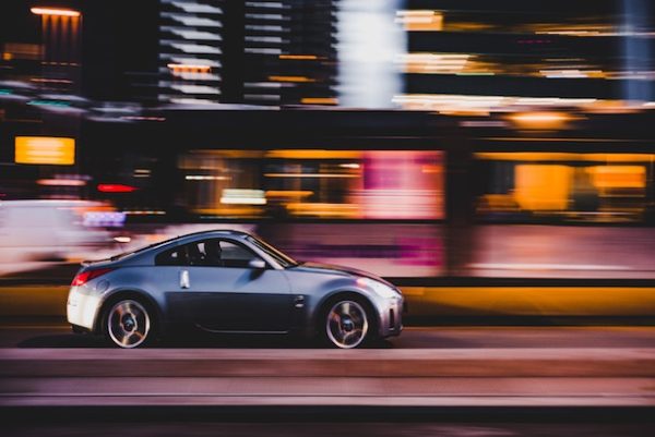 silver car speeding through a city at night