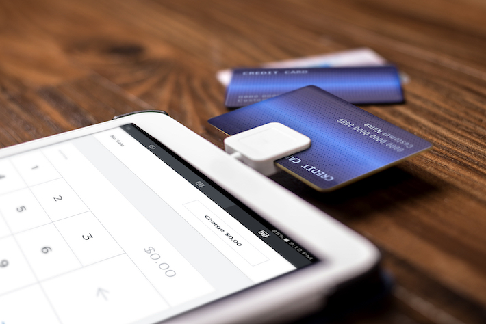 Credit card payment on a swipe or chip reader app on a tablet used by small or online businesses. The electronic device is used as a modern cash register or for banking.