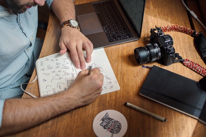 Man practices handwriting in a notebook, camera / art concept